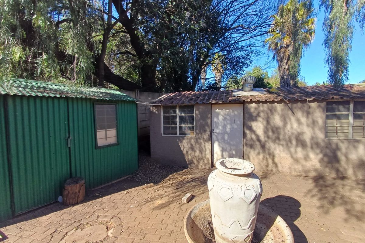 Rear courtyard area featuring a green corrugated metal shed and a secondary masonry outbuilding with a whirlybird roof ventilator.