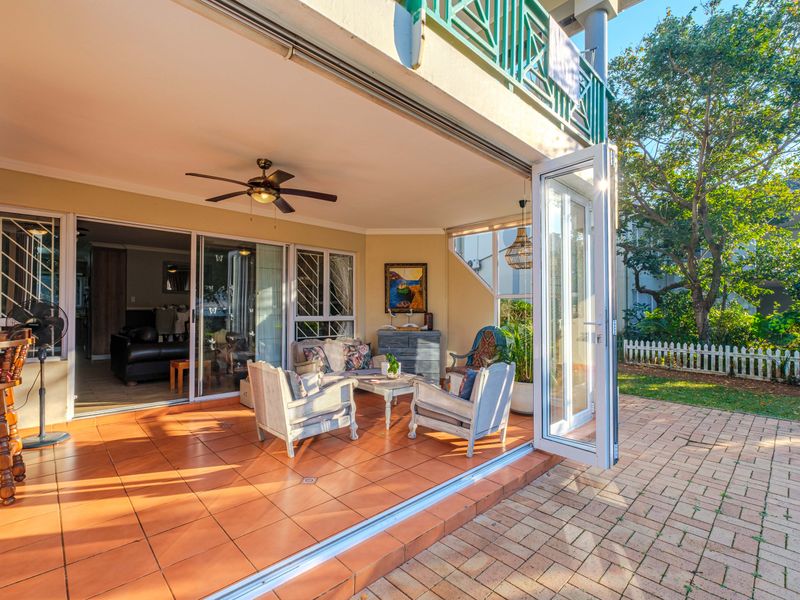 A spacious covered patio featuring terracotta tiling and large stacking glass doors that seamlessly connect the indoor living area to the private garden.