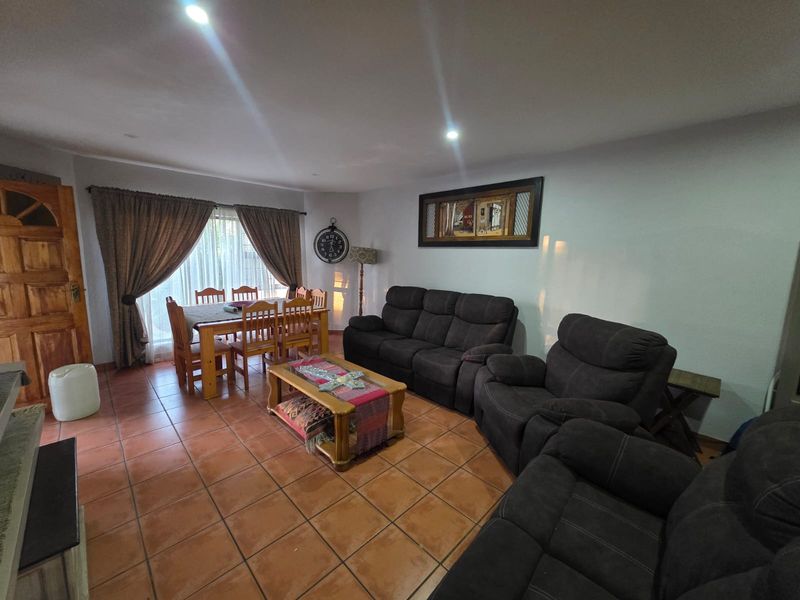 Open plan living and dining area featuring terracotta floor tiles and recessed downlighting, providing a functional space for relaxation and meals.