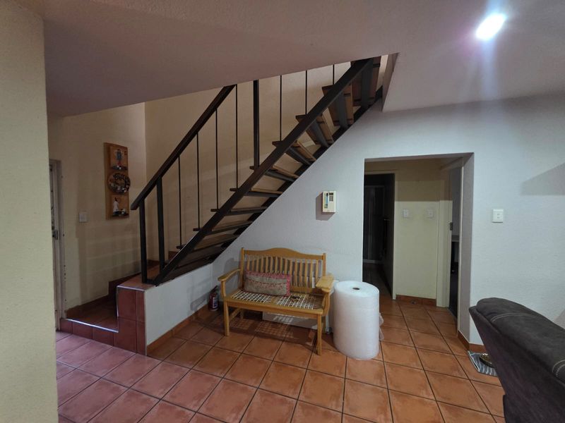 Living area featuring a staircase with a metal balustrade and terracotta floor tiles, providing access to the upper level of the townhouse.