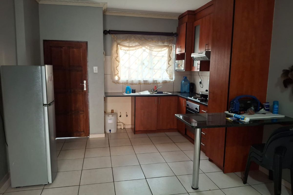 A functional kitchen featuring wooden cabinetry, built-in cooking appliances, a breakfast bar, and tiled flooring, offering a practical layout for daily meal preparation.