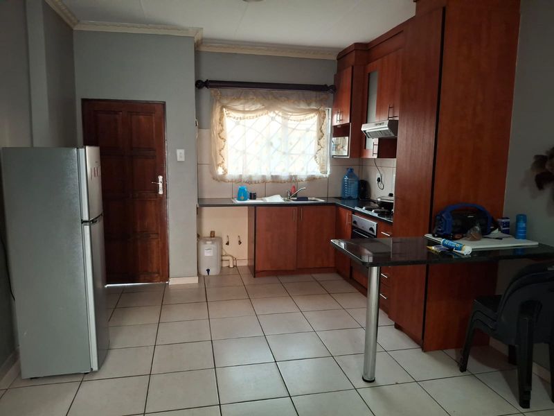 A functional kitchen featuring wooden cabinetry, built-in cooking appliances, a breakfast bar, and tiled flooring, offering a practical layout for daily meal preparation.