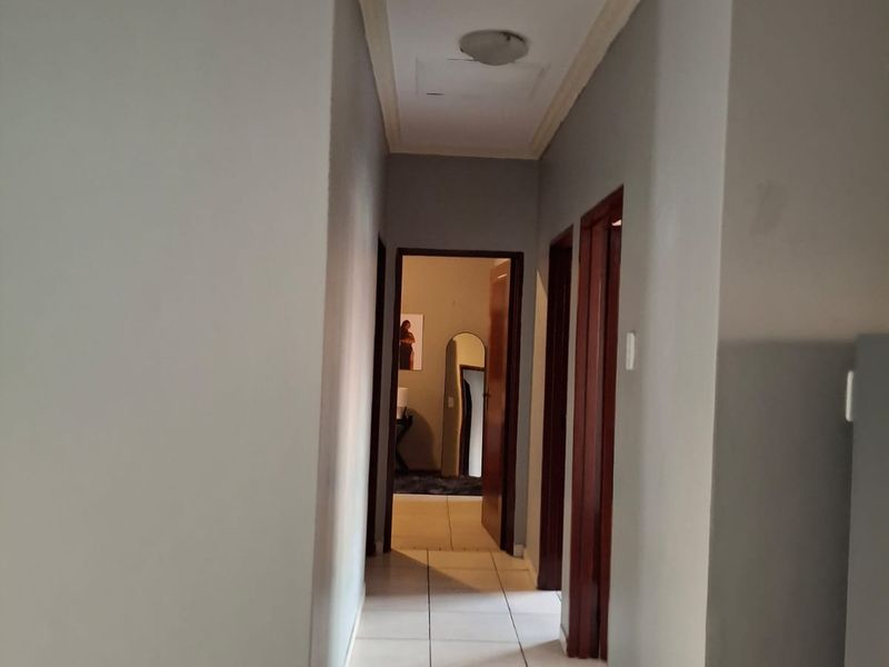 A functional hallway featuring tiled flooring, decorative ceiling cornices, and access to multiple rooms through wooden door frames.