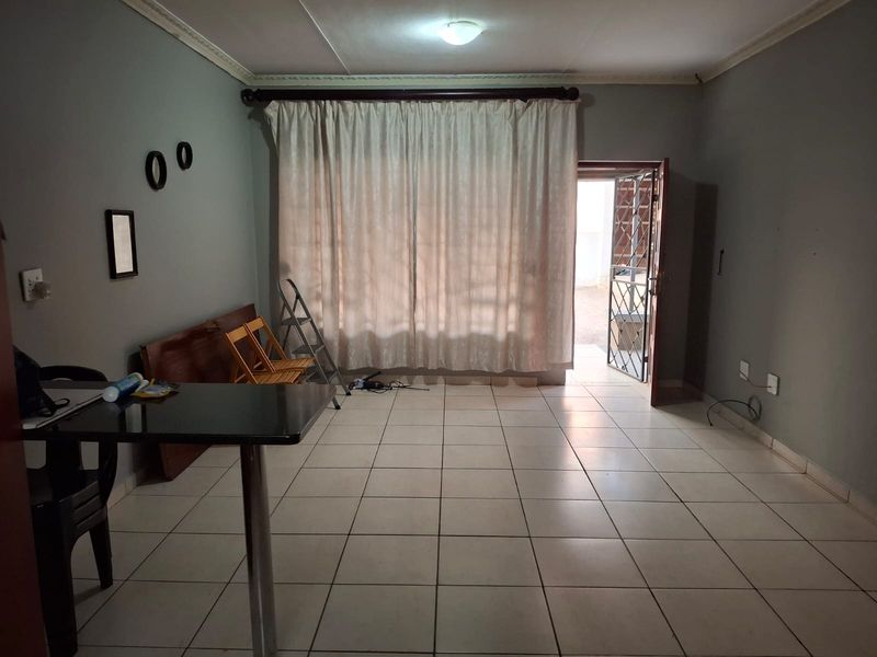 A living area featuring tiled flooring, ceiling cornice detailing, and direct access to the exterior through a security gate.