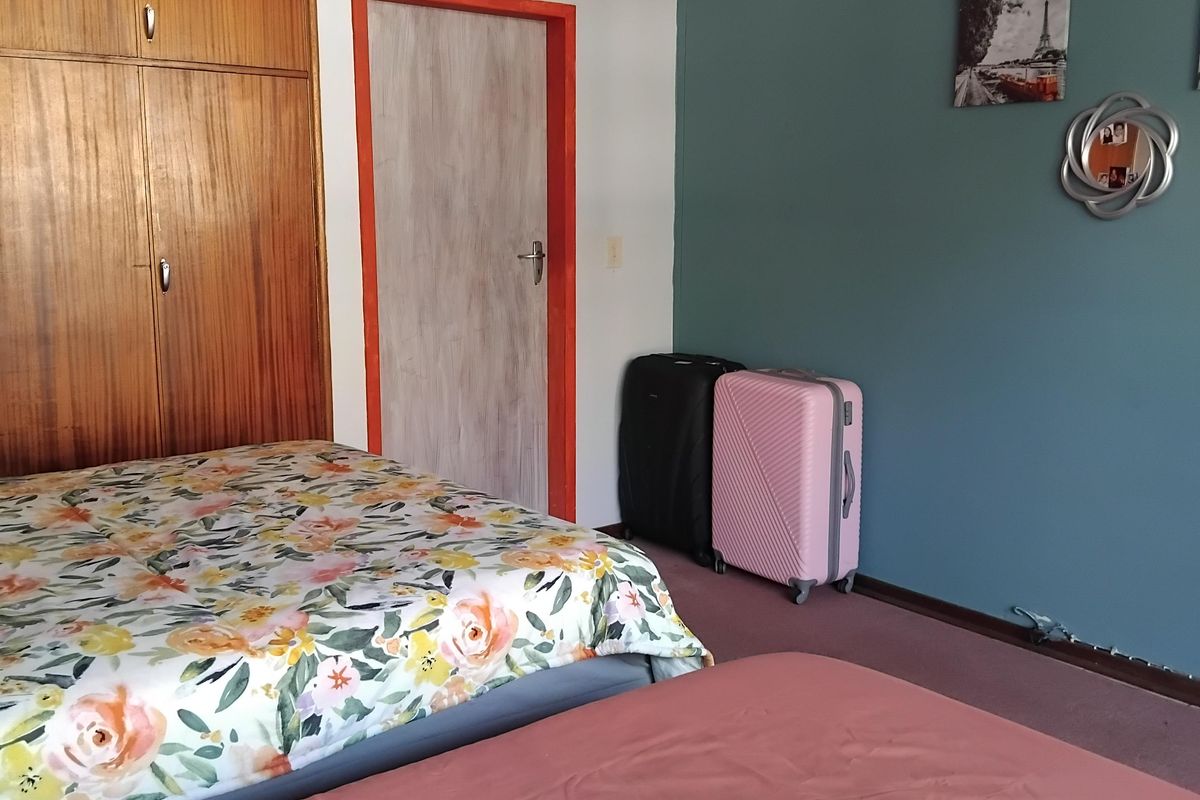 A bedroom featuring built-in wooden cupboards, carpeted flooring, and a blue accent wall, offering potential for modernization and aesthetic updates.