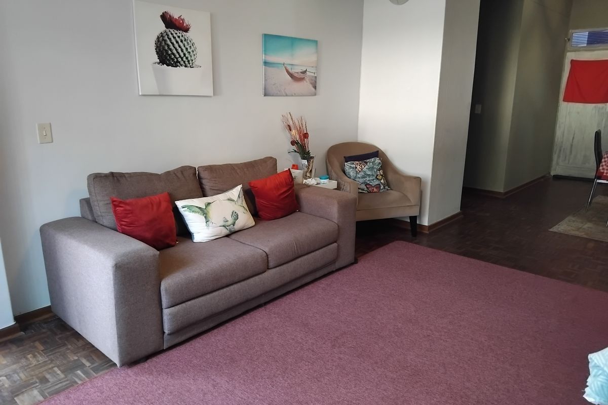 A comfortable living room area featuring classic parquet flooring and neutral wall finishes, providing a versatile space for relaxation.