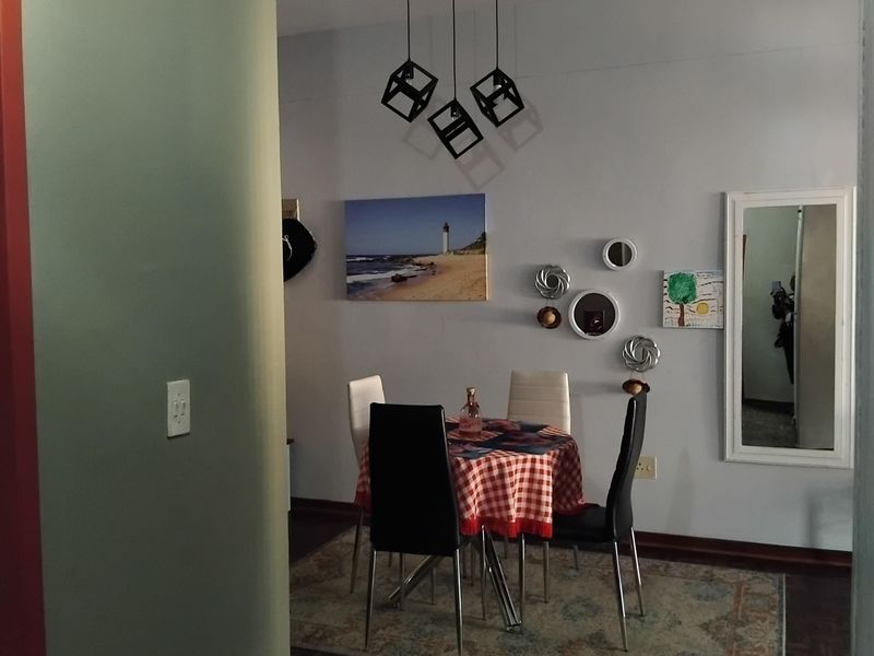 A dining area featuring classic parquet flooring and modern geometric pendant lighting, creating a cozy space for meals.