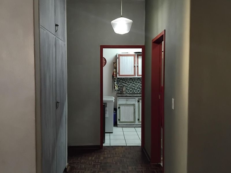 A functional hallway featuring parquet flooring and built-in storage cupboards, providing access to the kitchen area.