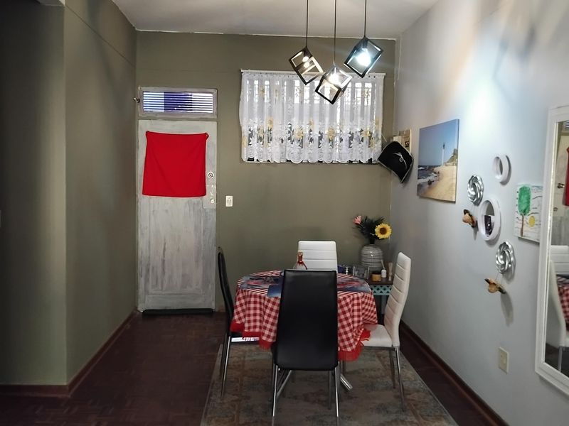 A dining area featuring classic parquet flooring, a modern geometric pendant light fixture, and a transom window above the entrance door.