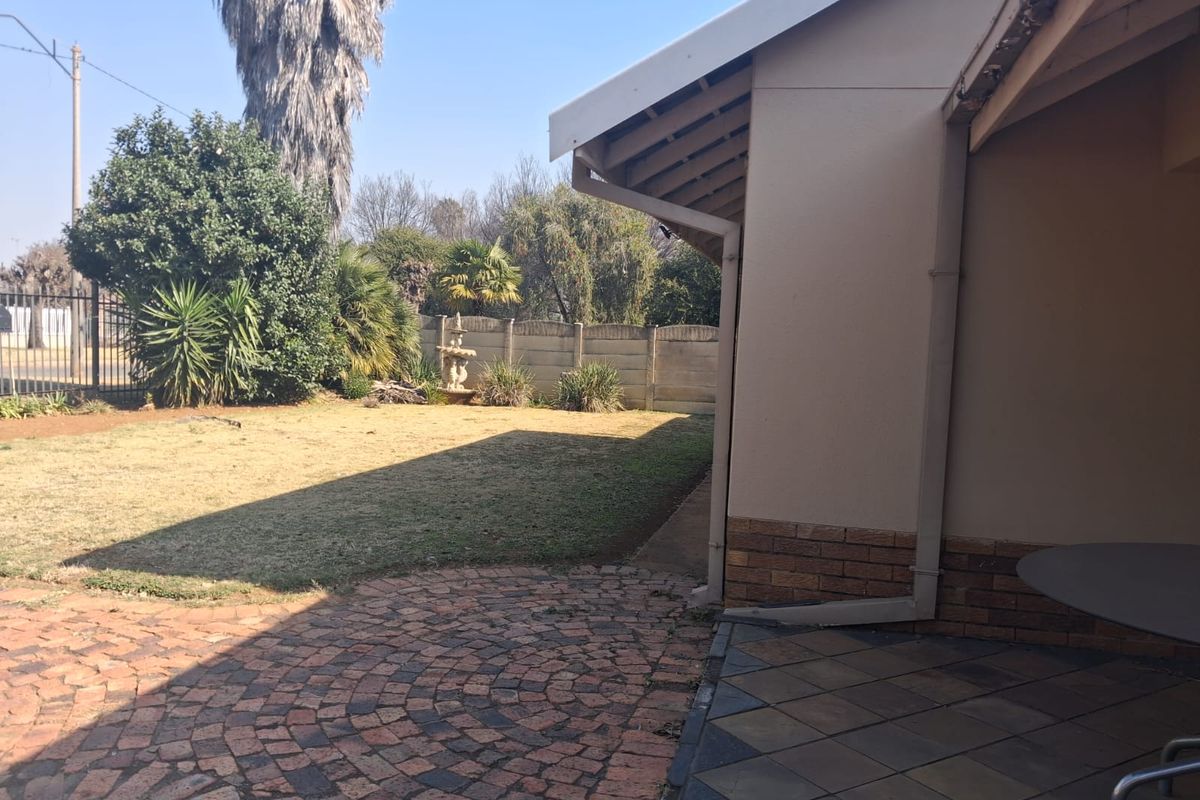 Rear garden area featuring a brick-paved patio, tiled outdoor space, and a precast concrete boundary wall.