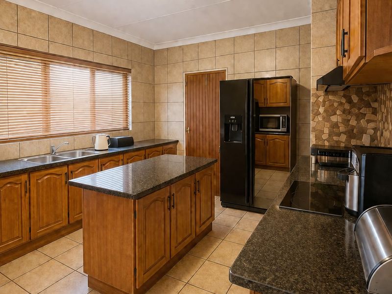 A functional kitchen featuring wooden cabinetry, granite countertops, a central island, and tiled finishes throughout.