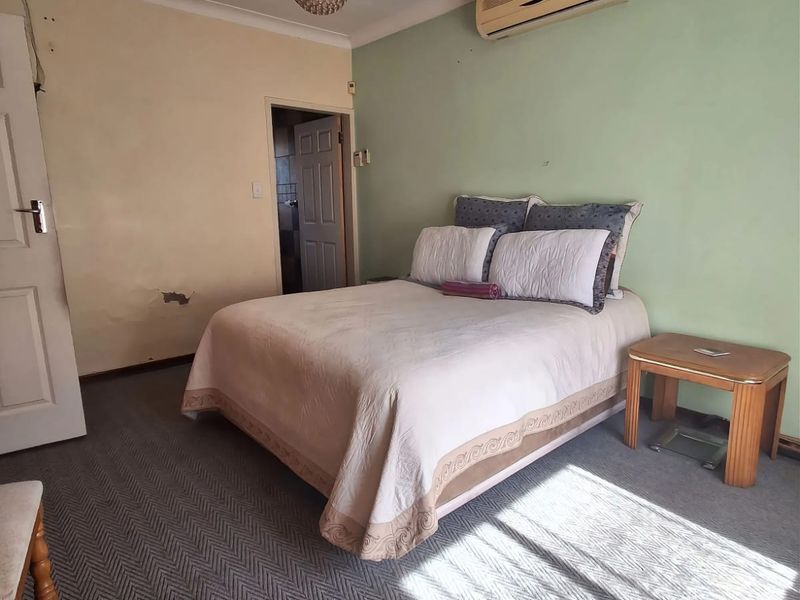 A bedroom featuring carpeted flooring, a split-system air conditioner, and coved ceilings, requiring cosmetic updates to the wall finishes.