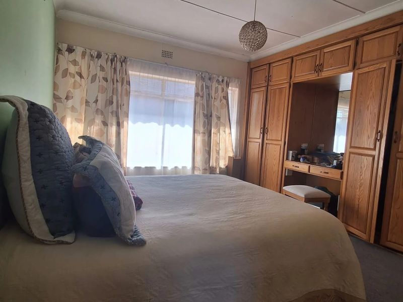 A bedroom featuring a large built-in wooden wardrobe with an integrated vanity unit and a wall-mounted air conditioning unit.