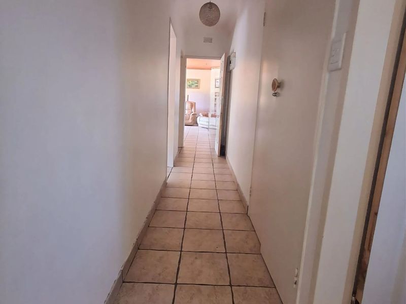 A functional hallway featuring neutral tiled flooring and a ceiling access hatch, providing a clean transition between the home's living spaces.