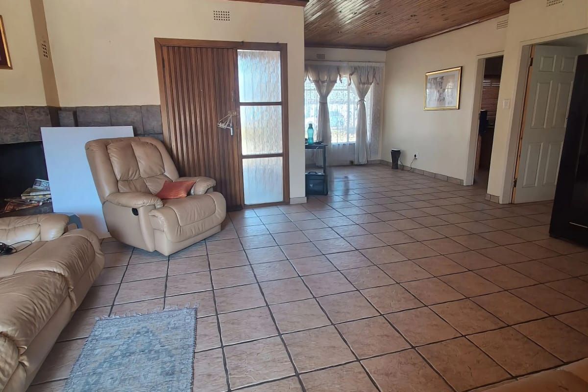 Spacious living room featuring a timber tongue and groove ceiling, tiled flooring, and a built-in fireplace, offering a functional and open layout.