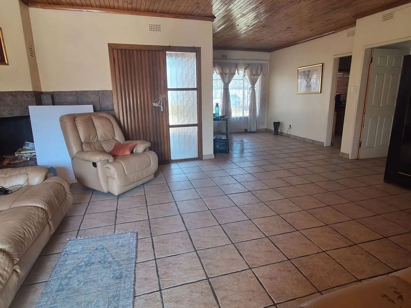 Spacious living room featuring a timber tongue and groove ceiling, tiled flooring, and a built-in fireplace, offering a functional and open layout.
