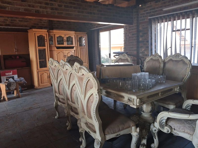 Dining room featuring exposed brick walls, timber ceiling beams, and tiled flooring with access to the outdoors via a sliding glass door.