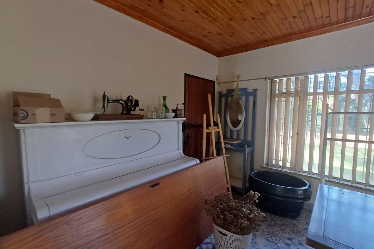 A living area featuring a timber tongue and groove ceiling and patterned ceramic floor tiles, offering a dated but functional space.