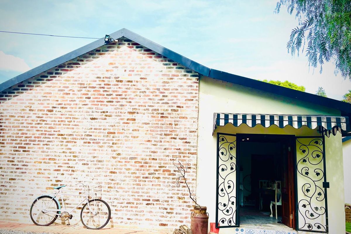 Rear exterior view of the property featuring exposed brickwork, a decorative wrought iron security gate, and a classic striped fabric awning over the entrance.