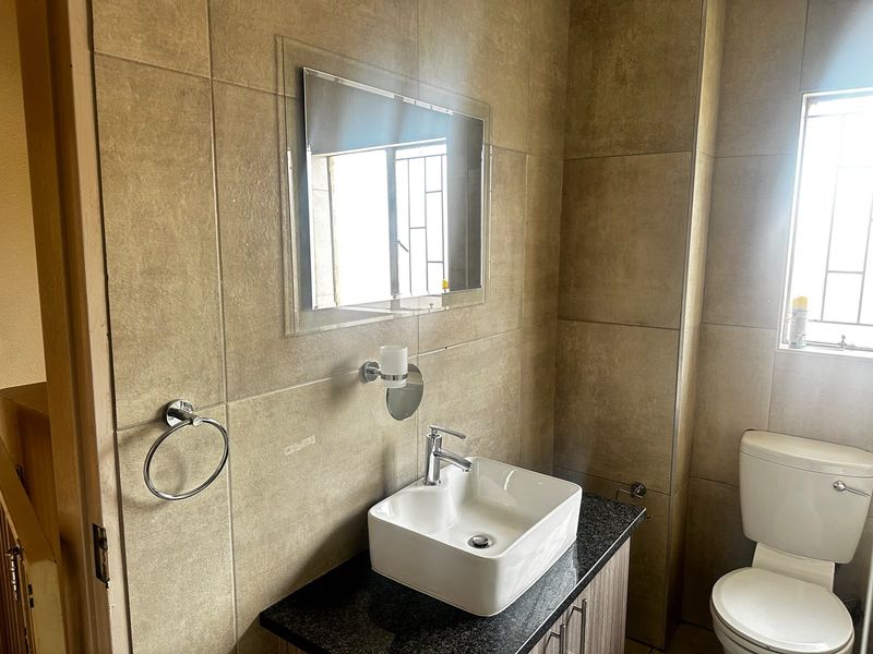 A modern bathroom featuring a vessel sink on a granite vanity, tiled walls, and a toilet, providing a clean and functional space.