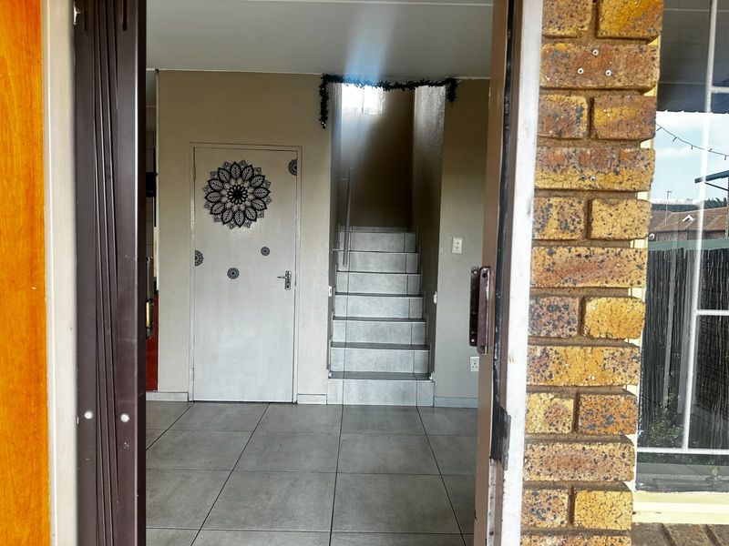 An entry area featuring tiled flooring and a staircase with a metal handrail, providing access to the upper level of the townhouse.