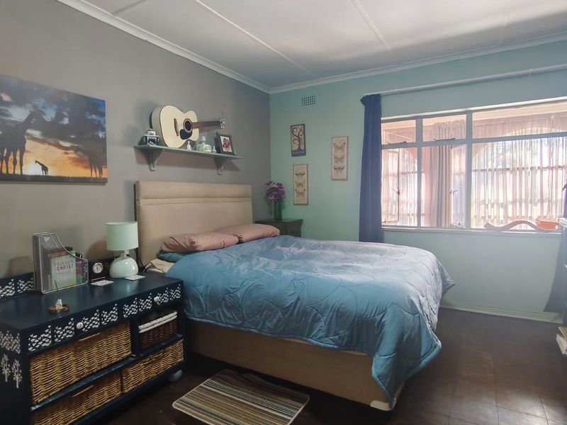 A bedroom featuring a large window, tiled flooring, and a ceiling light fixture. The room offers a functional space with potential for cosmetic updates.