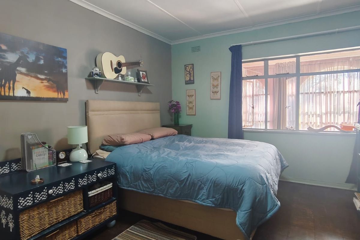 A bedroom featuring a large window, tiled flooring, and a ceiling light fixture. The room offers a functional space with potential for cosmetic updates.