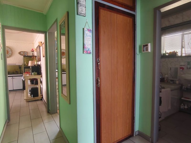 A central hallway featuring tiled flooring, timber panelled ceilings, and access to adjacent rooms, including a bathroom and living area.