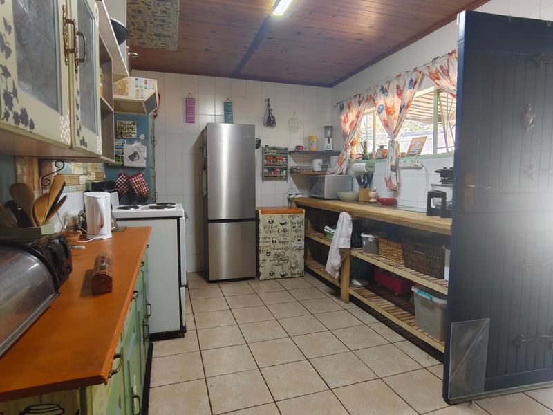 A functional kitchen featuring tiled flooring, timber ceiling, and ample built-in cabinetry with a freestanding stove and open shelving storage.