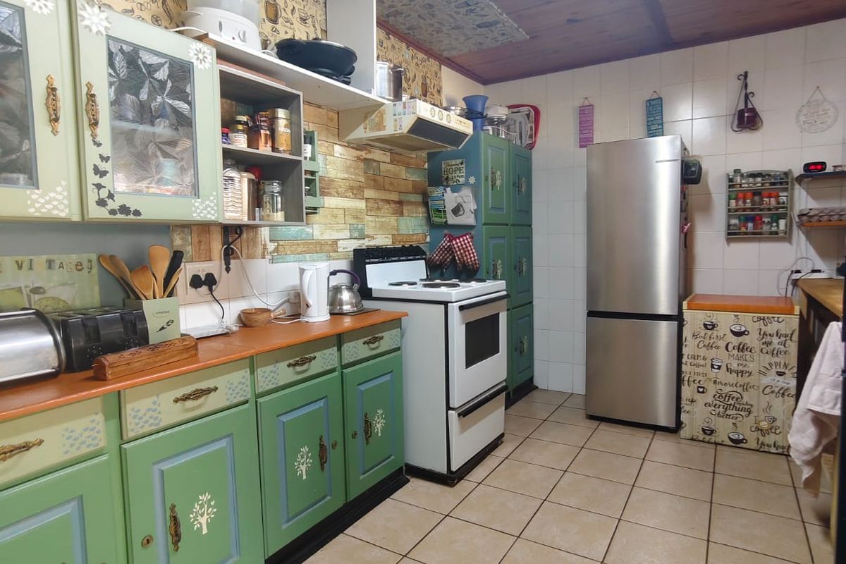 A dated kitchen featuring green cabinetry, tiled flooring, and a timber ceiling, offering significant potential for modernization and renovation.