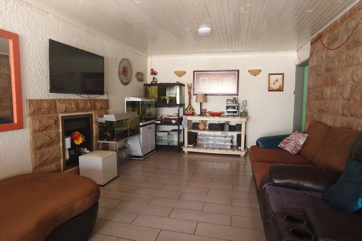 Living room featuring a stone fireplace, stone feature wall, and timber ceiling with tiled flooring.