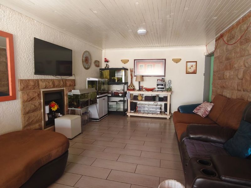 Living room featuring a stone fireplace, stone feature wall, and timber ceiling with tiled flooring.