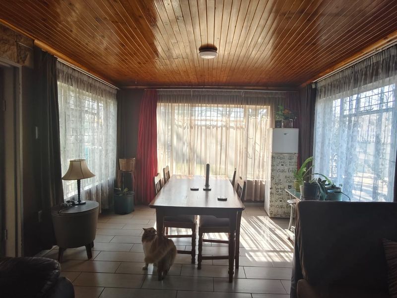 A dining room featuring a polished timber tongue and groove ceiling, ceramic tiled flooring, and large windows providing ample natural light.
