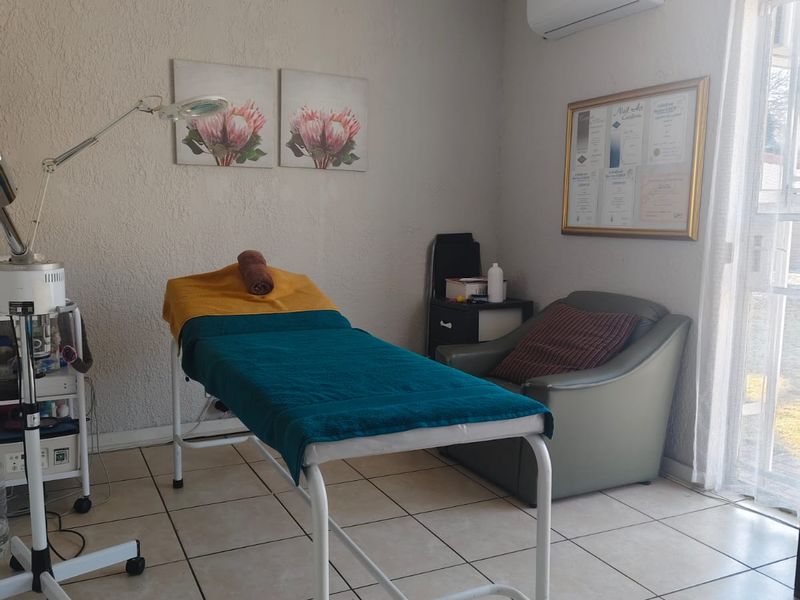 A functional room currently utilized as a treatment space, featuring tiled flooring, a ceiling fan, and a wall-mounted air conditioning unit.