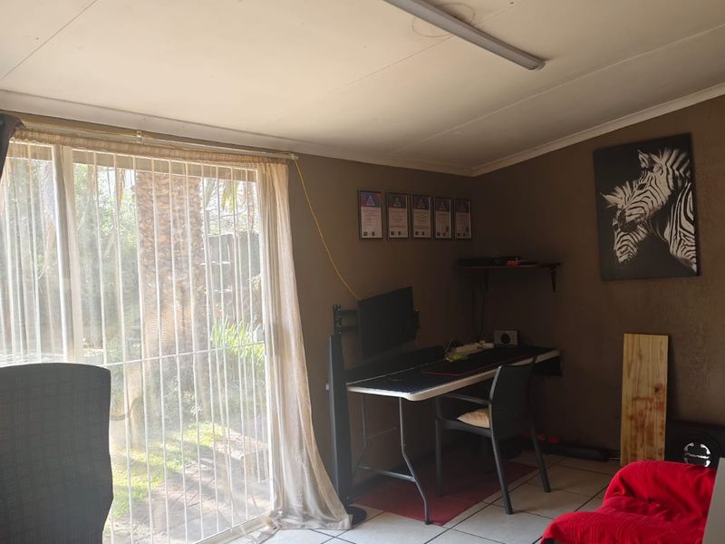 A functional home office space featuring tiled flooring and a large sliding glass door providing natural light and garden access.