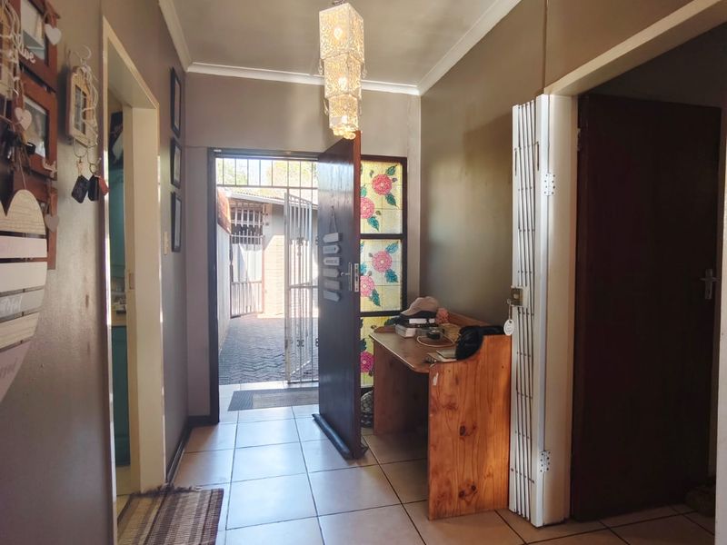 A tiled entrance hallway featuring a decorative pendant light, stained glass door detail, and access to the exterior through a security gate.