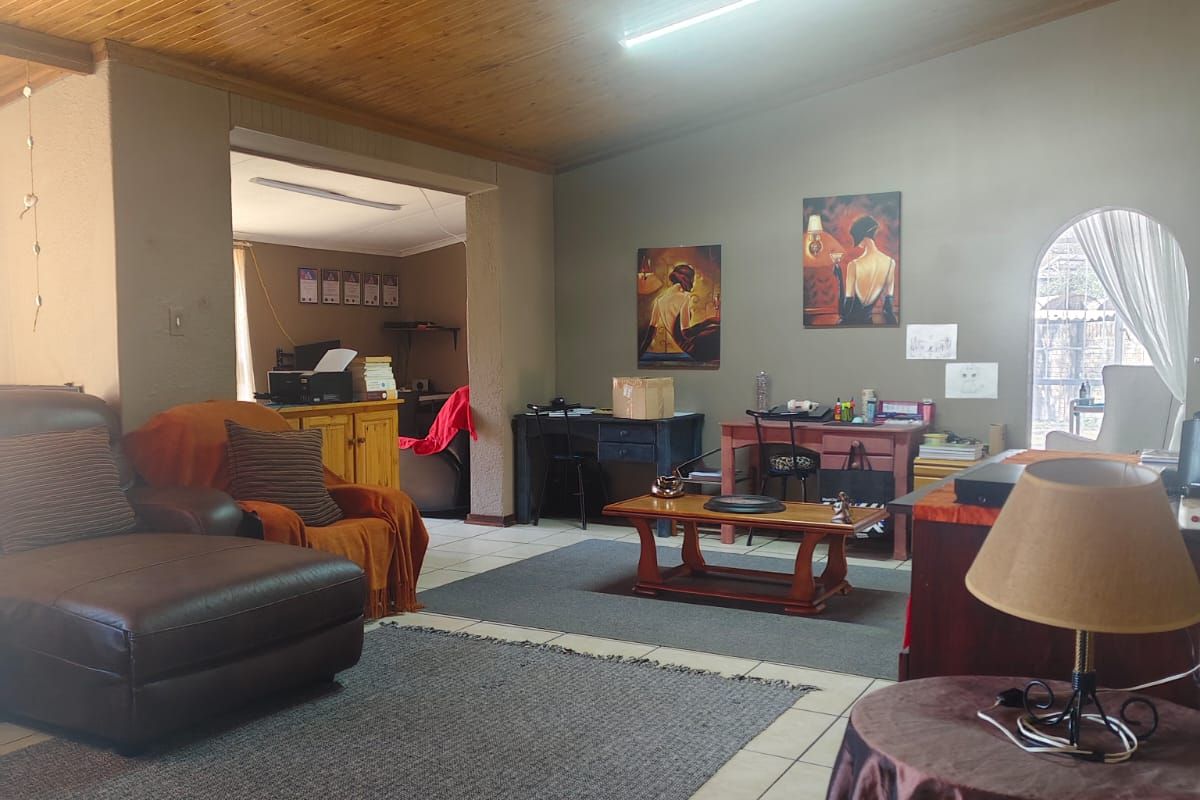Spacious living area featuring a timber-clad ceiling, ceramic floor tiles, and an arched window, offering a versatile layout for comfortable family living.