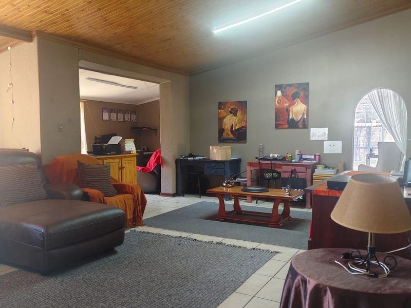 Spacious living area featuring a timber-clad ceiling, ceramic floor tiles, and an arched window, offering a versatile layout for comfortable family living.