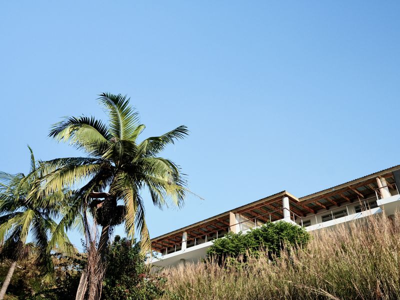 A low-angle view of the rear elevation of the apartment building, featuring a balcony with railings and an exposed roof structure.