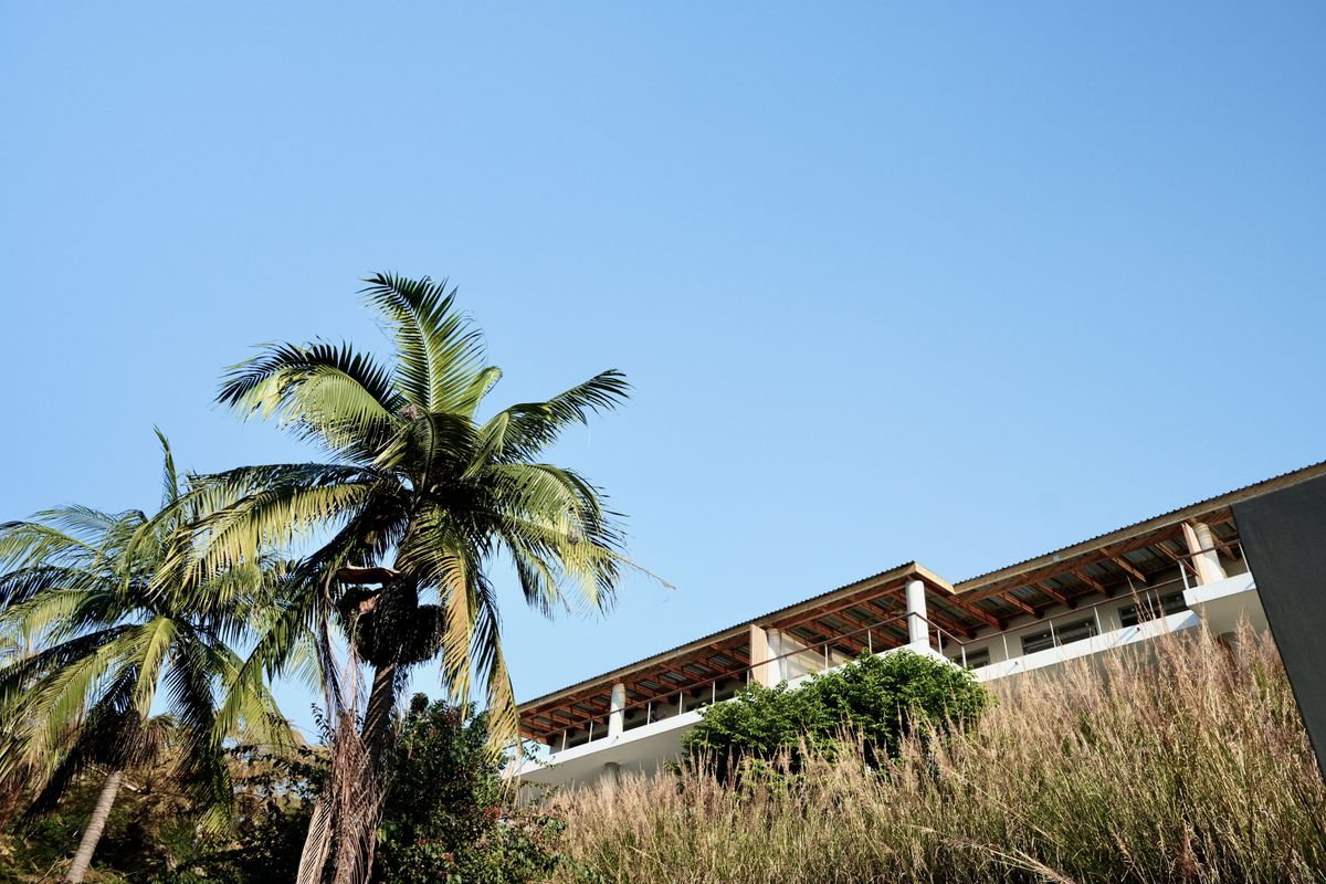 A low-angle view of the rear elevation of the apartment building, featuring a balcony with railings and an exposed roof structure.