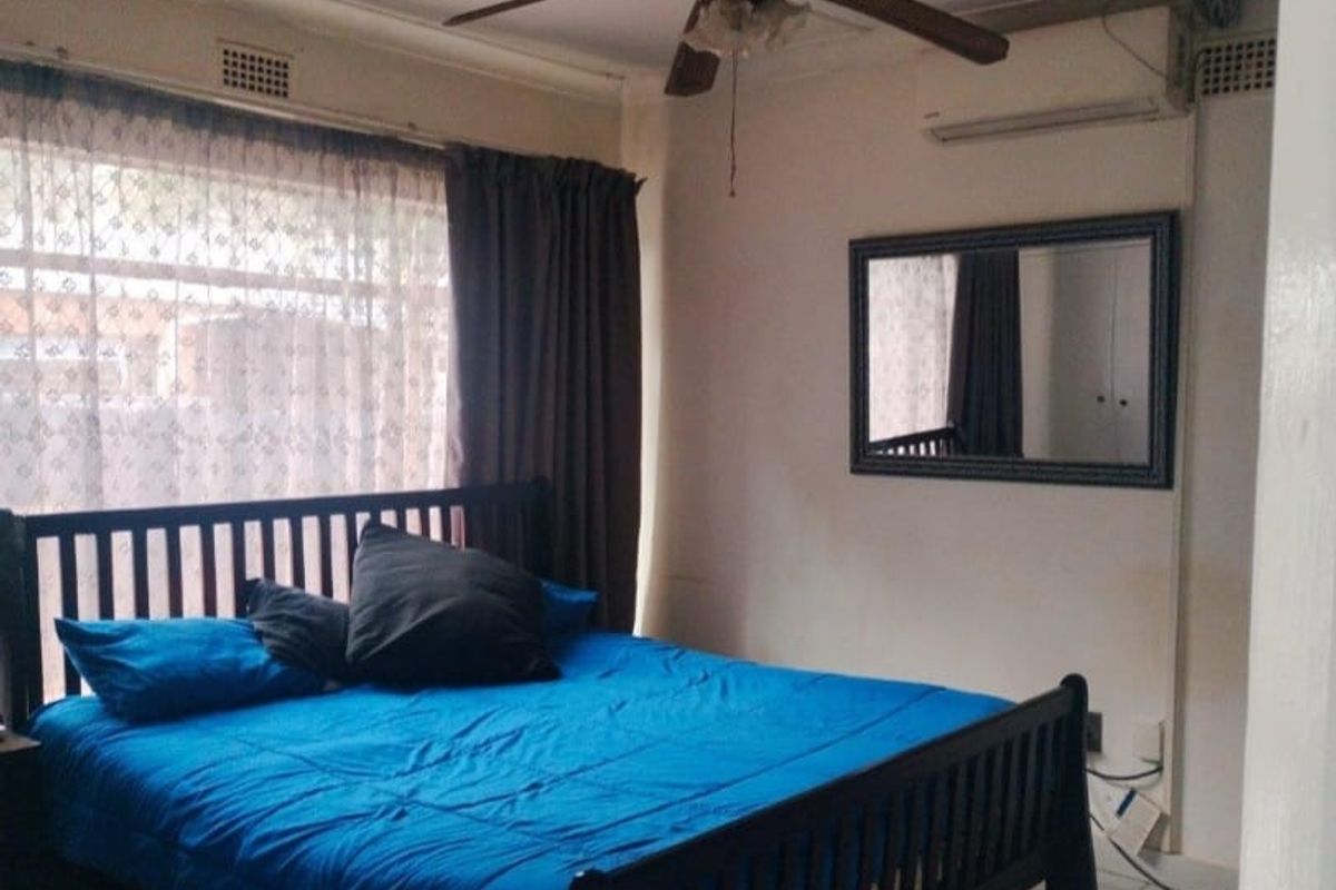 A bedroom featuring tiled flooring, a ceiling fan, and a wall-mounted split-system air conditioner.