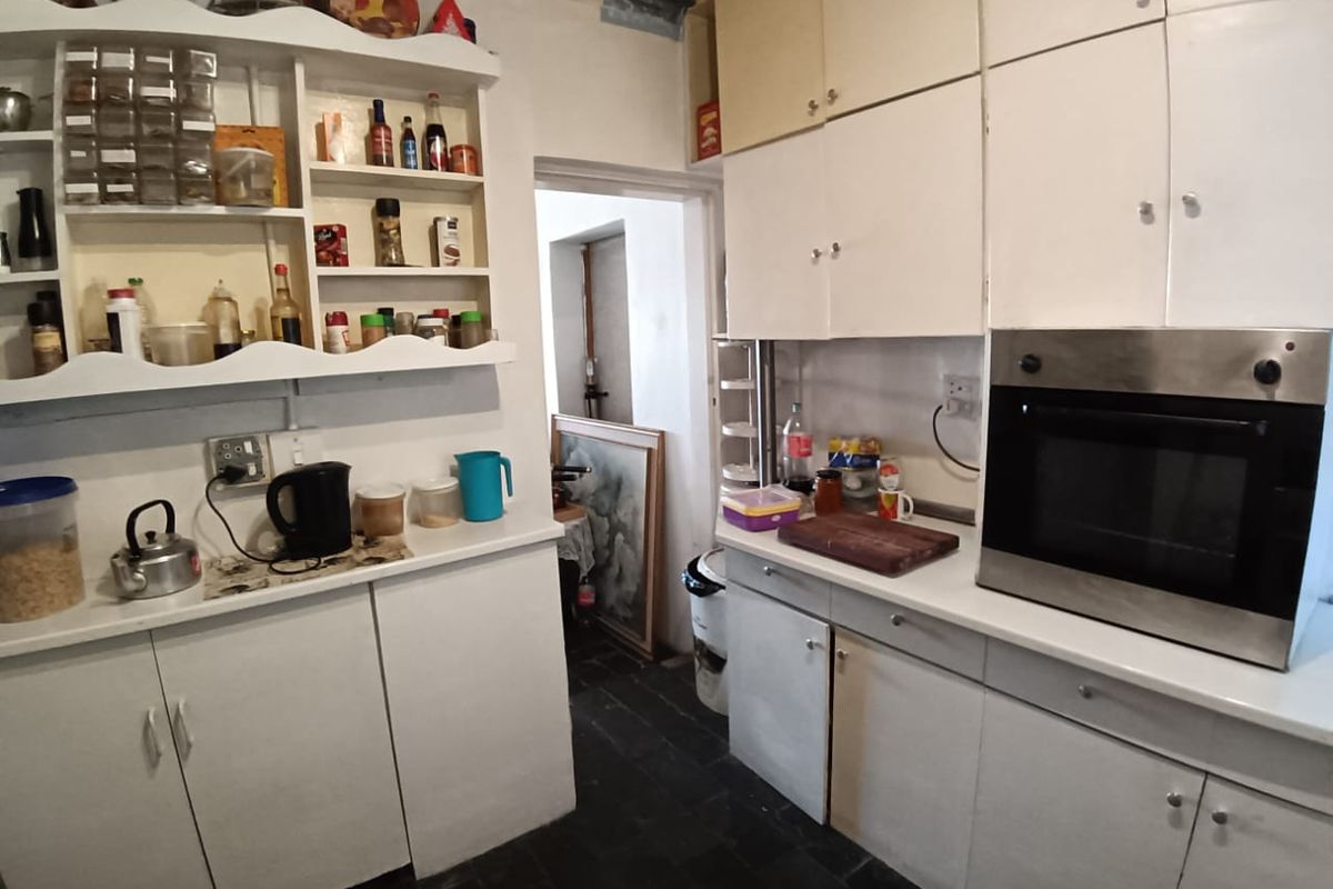A functional kitchen featuring white built-in cabinetry, open shelving, a built-in oven, and dark tiled flooring, offering potential for a modern renovation.