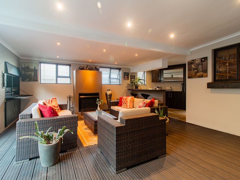 Covered patio area featuring composite decking, a built-in braai, a fireplace, and an integrated breakfast bar with kitchen cabinetry.