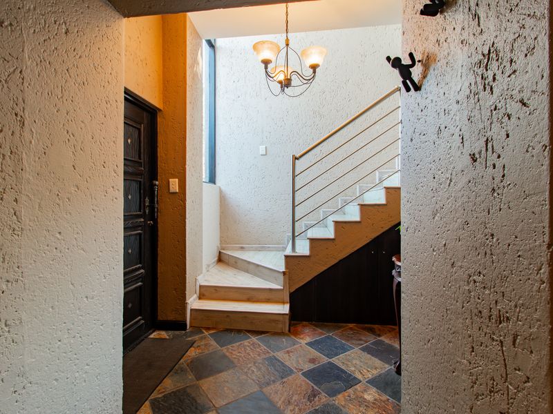 Welcoming entrance hall featuring slate tile flooring, a textured wall finish, and a staircase with a modern stainless steel balustrade.