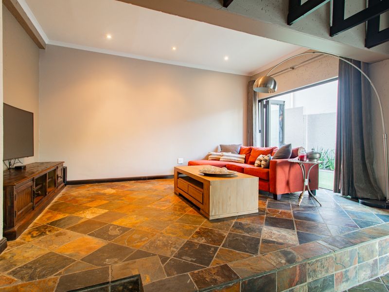 Spacious living room featuring natural slate tile flooring, recessed lighting, and a large sliding glass door providing access to the outdoor area.