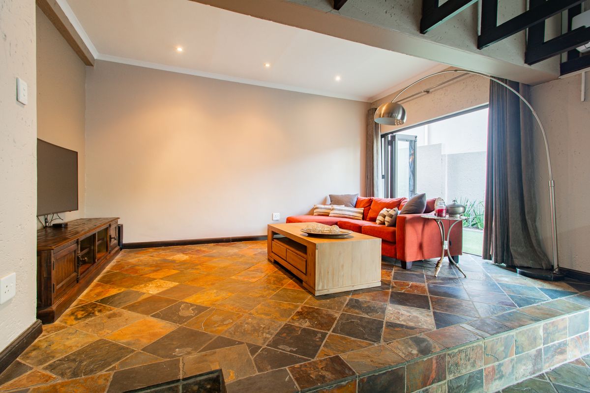 Spacious living room featuring natural slate tile flooring, recessed lighting, and a large sliding glass door providing access to the outdoor area.