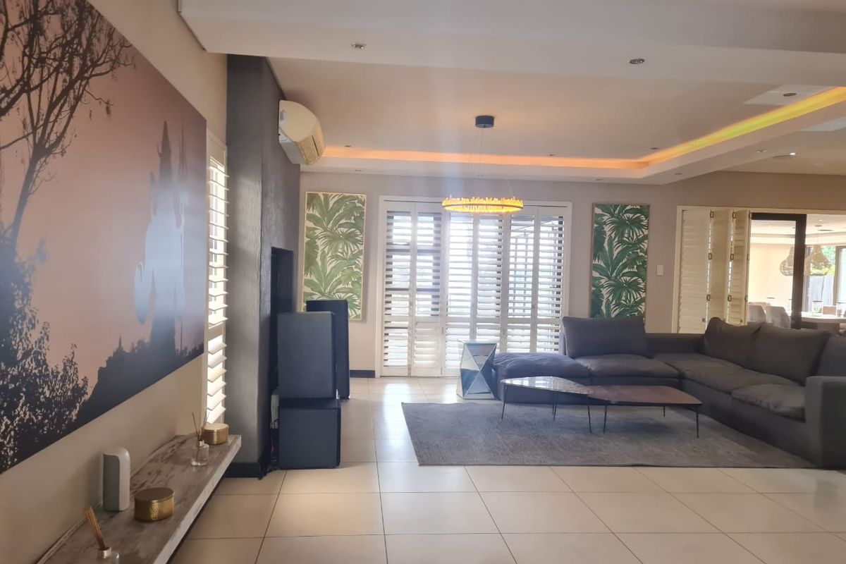 Spacious living room featuring tiled flooring, recessed ceiling lighting with cove accents, and plantation shutters, creating a bright and modern atmosphere.