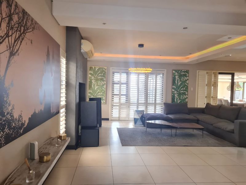 Spacious living room featuring tiled flooring, recessed ceiling lighting with cove accents, and plantation shutters, creating a bright and modern atmosphere.