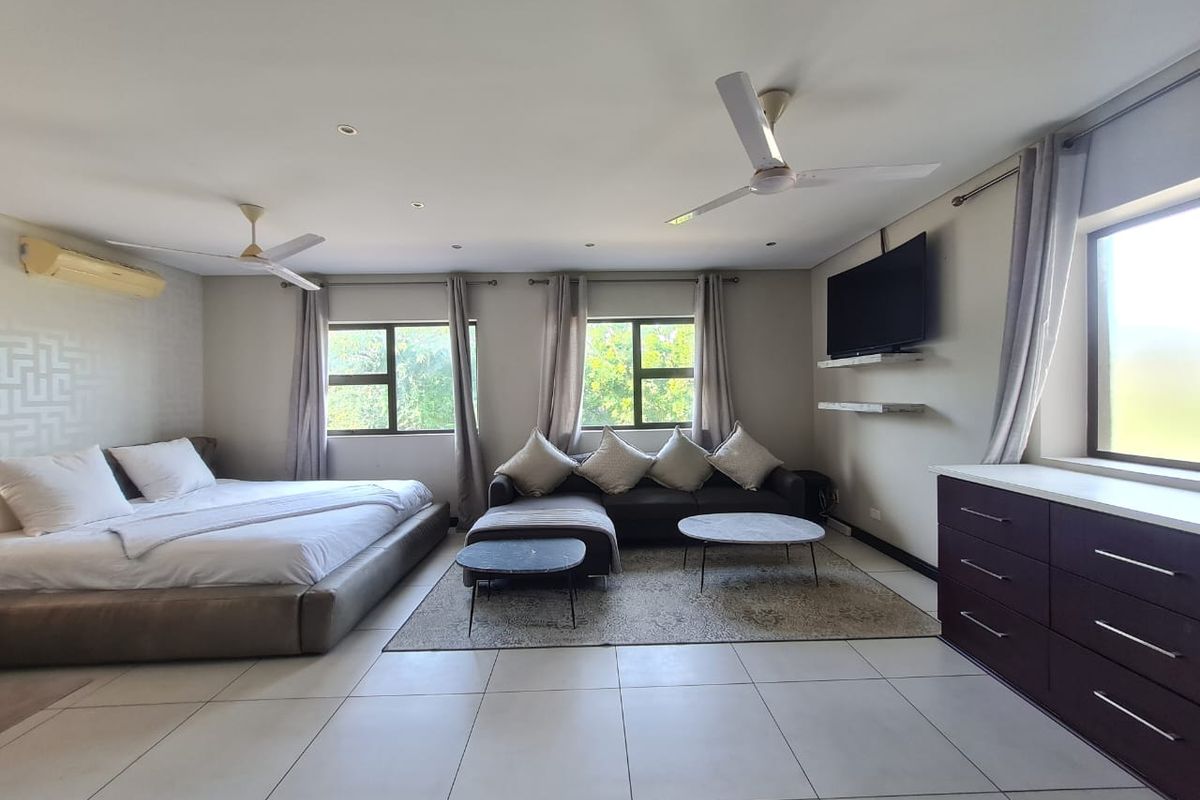 Spacious bedroom featuring tiled flooring, dual ceiling fans, split-system air conditioning, and large windows providing ample natural light.