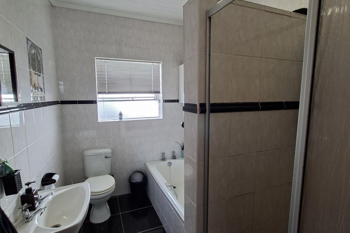 A functional bathroom featuring a pedestal basin, toilet, bathtub, and a separate shower enclosure with tiled finishes throughout.